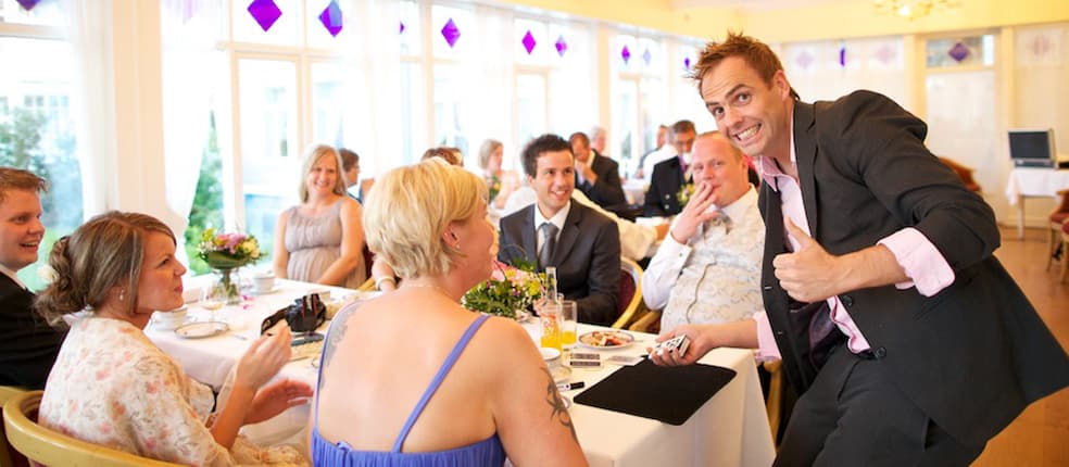 Rune Carlsen underholder brudepar og bryllupsgjester med bordtrylling.