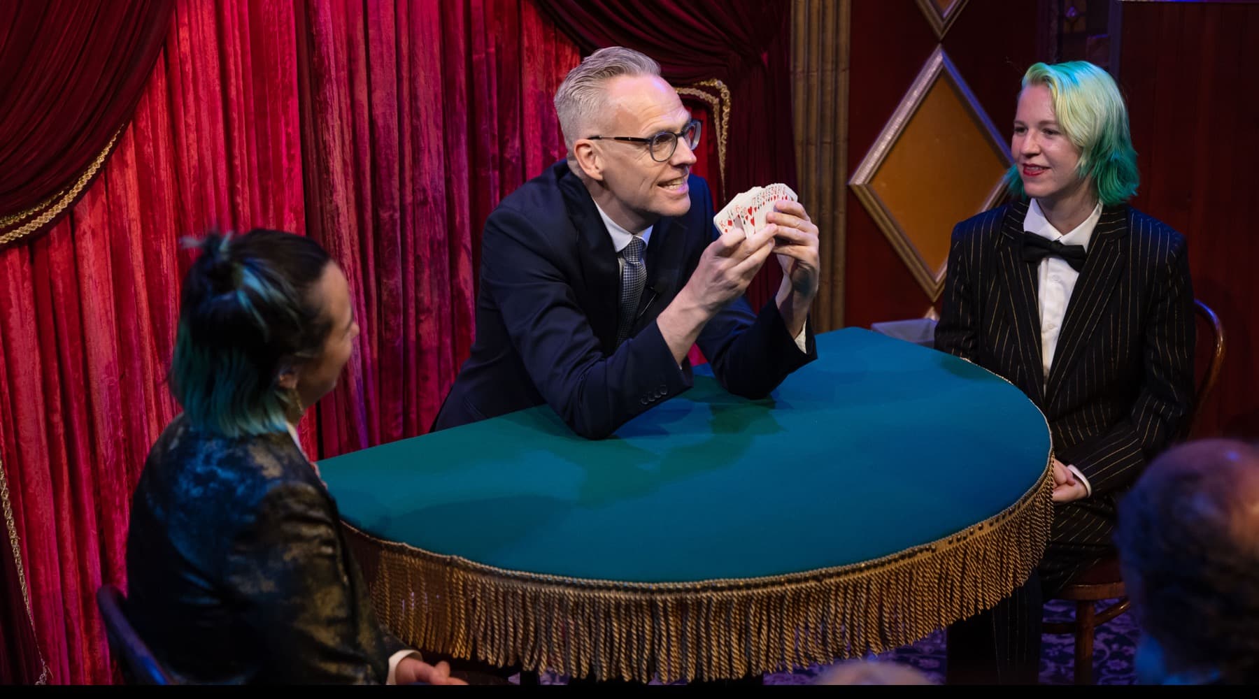 Rune Carlsen underholder gjester tett på med kortmagi rundt et bord.